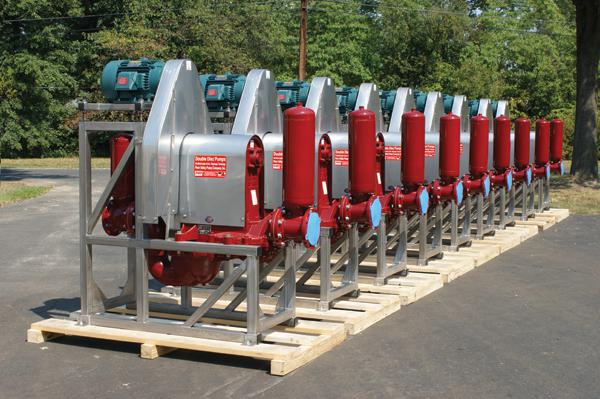 a row of large new red and silver pumps sitting on pallets outside